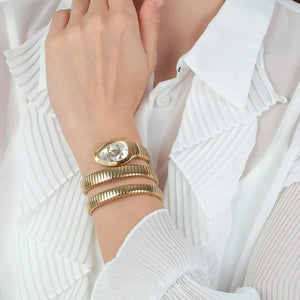 Gold bracelets on a wrist with a white background