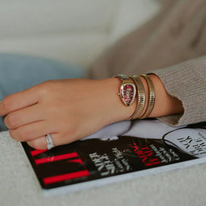 Person wearing gold bracelets on a book with text