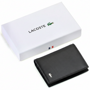 A closed Lacoste men's black smooth leather wallet featuring a silver metal crocodile logo, placed elegantly next to its matching closed white gift box