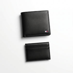 Straight front view product photography of the Tommy Hilfiger mirror original black leather wallet alongside its matching slim card case with vertical ribbon details