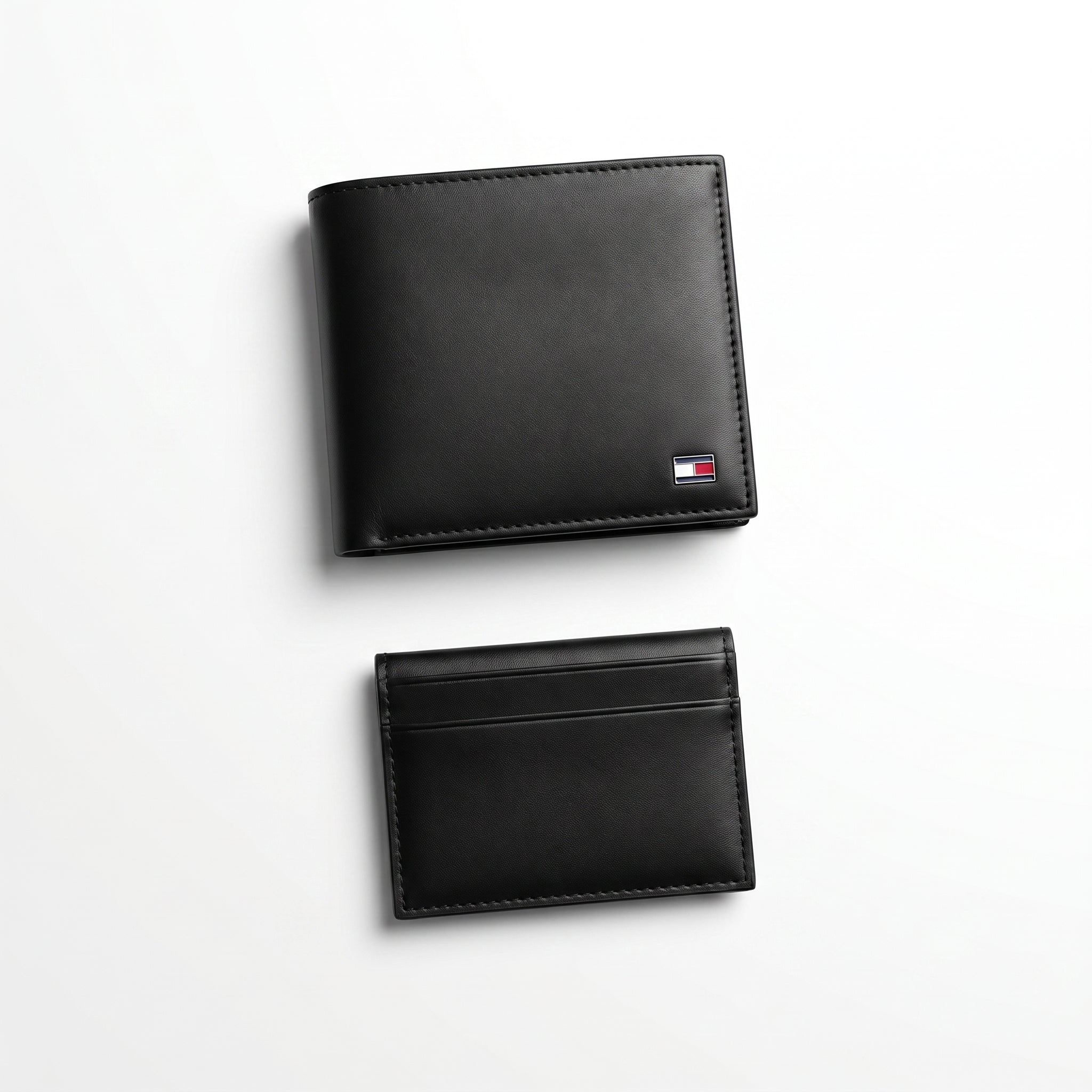 Straight front view product photography of the Tommy Hilfiger mirror original black leather wallet alongside its matching slim card case with vertical ribbon details