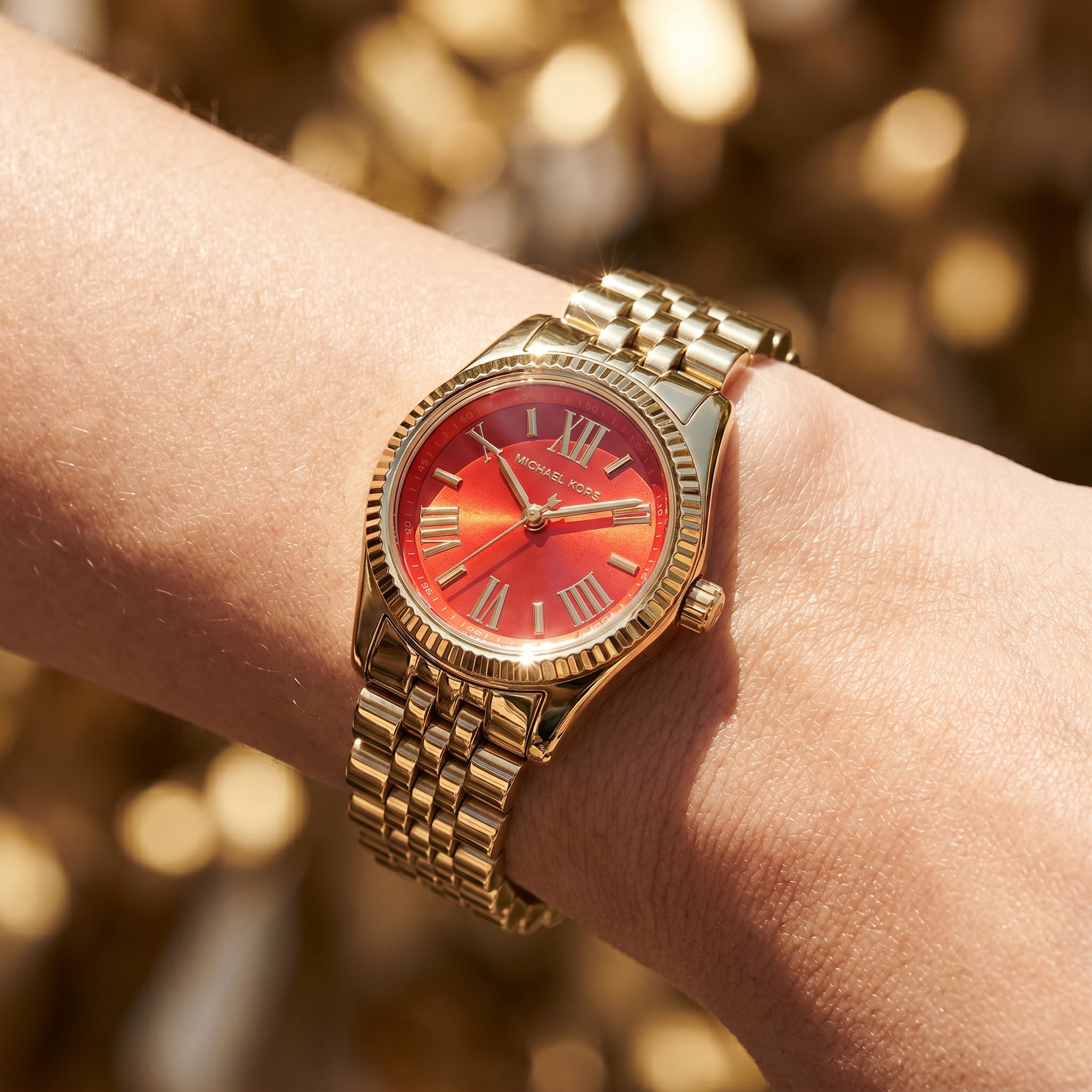 Close up shot of Michael Kors MK3284 on wrist showing the gold case and red Roman numeral dial