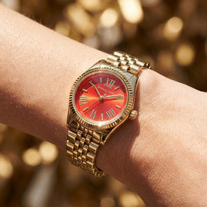 Close up shot of Michael Kors MK3284 on wrist showing the gold case and red Roman numeral dial