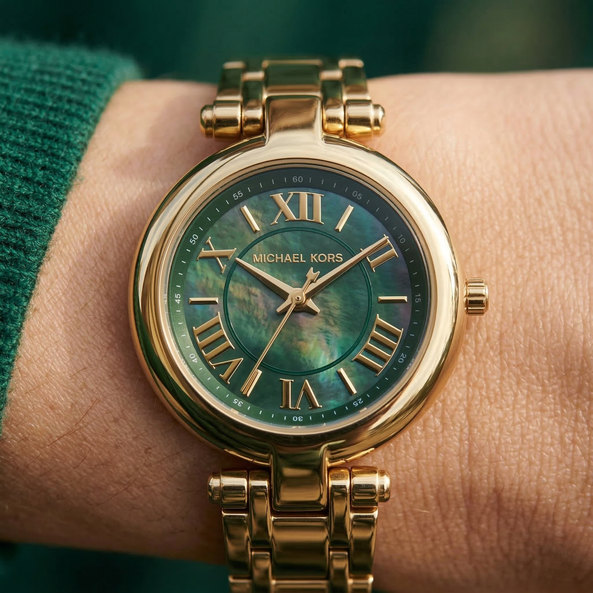 Close up of Michael Kors Lennox MK4892 women's quartz battery watch on wrist showing emerald green mother of pearl dial and gold metal bracelet
