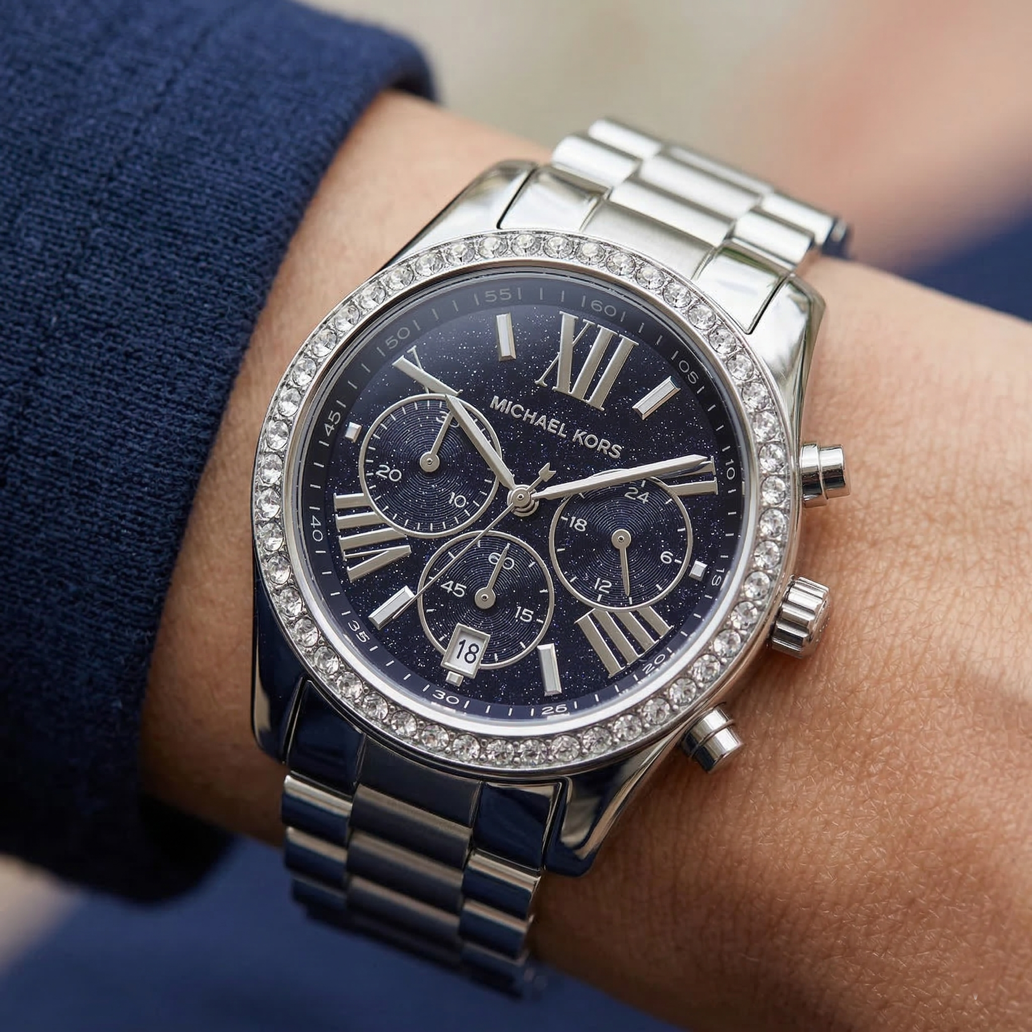 Close up of Michael Kors Lexington MK7277 women's quartz battery watch on wrist showing navy blue glitter dial and brilliant crystal bezel