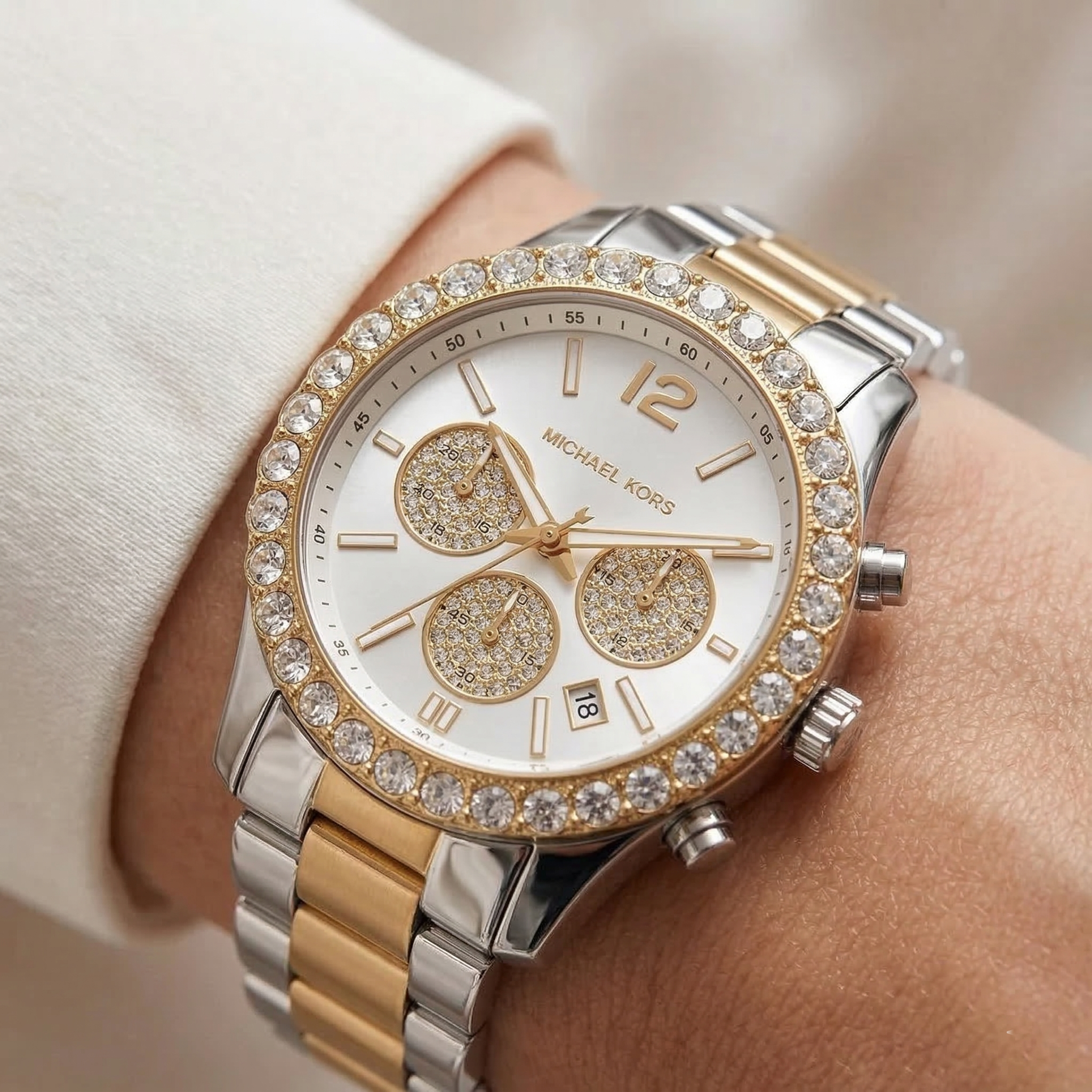 Close up of Michael Kors Everest MK7415 on wrist showing white sunray dial with crystal pavé sub-dials and two-tone metal bracelet