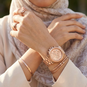 Elegant woman wearing Michael Kors Maren MK7494 women's quartz battery watch with rose gold-tone case and luxury logo bezel