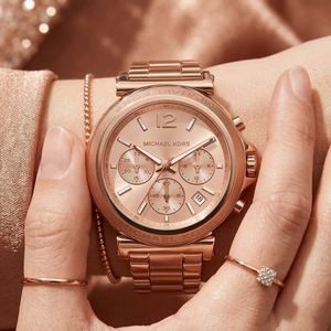 Close up of Michael Kors Maren MK7494 women's quartz battery watch on wrist showing rose gold sunray dial and metal bracelet