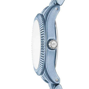 Close-up side view of a Michael Kors watch with a metallic blue case, textured bezel, and silver MK logo on the crown, set against a plain white background.
