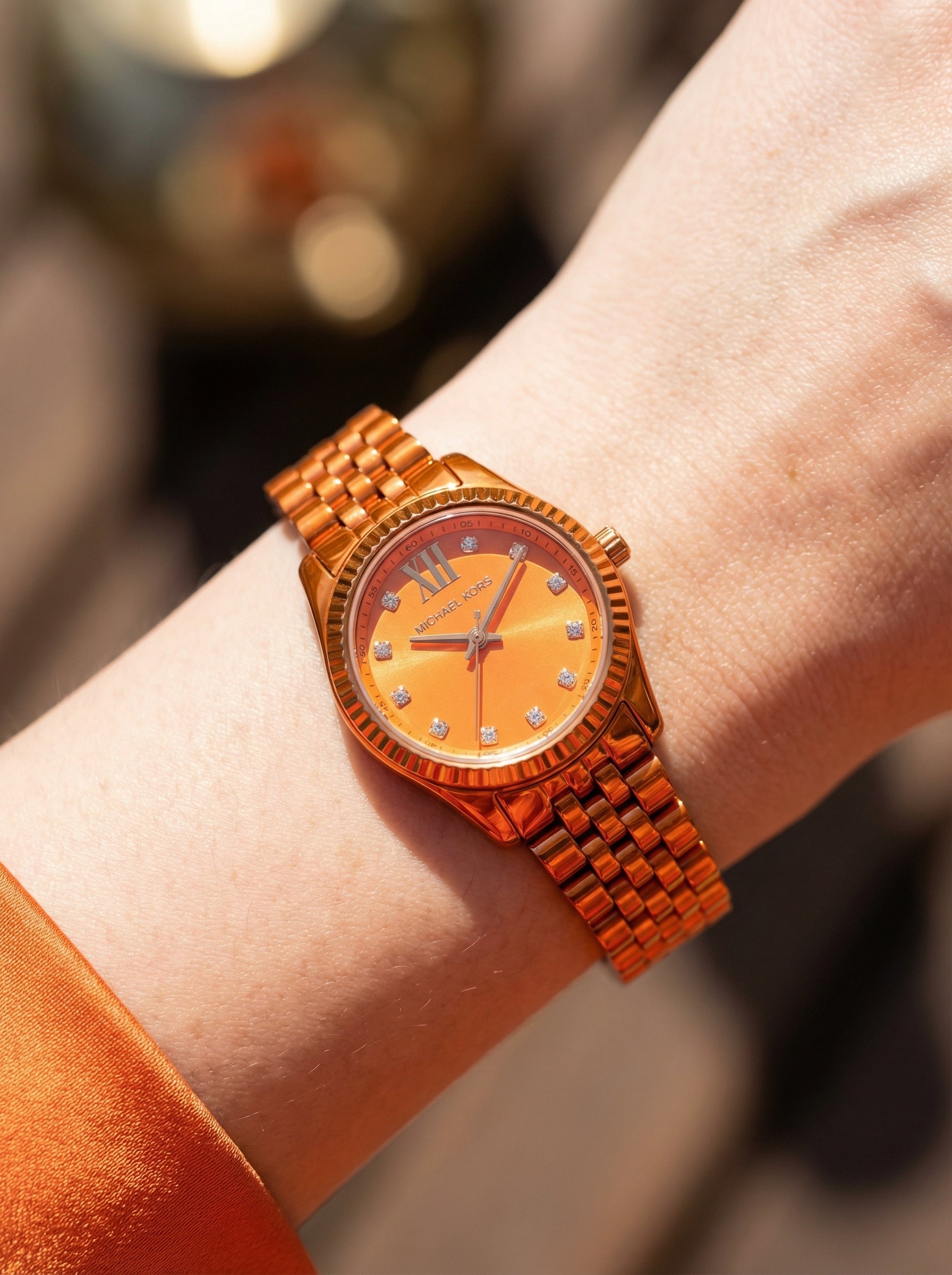 Close up shot of Michael Kors MK7538LE on wrist showing petite 26mm case and orange dial