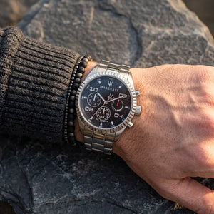 Close up of Maserati Competizione R8853100012 men's quartz battery watch on wrist showing black carbon fiber multi-function dial and silver metal bracelet