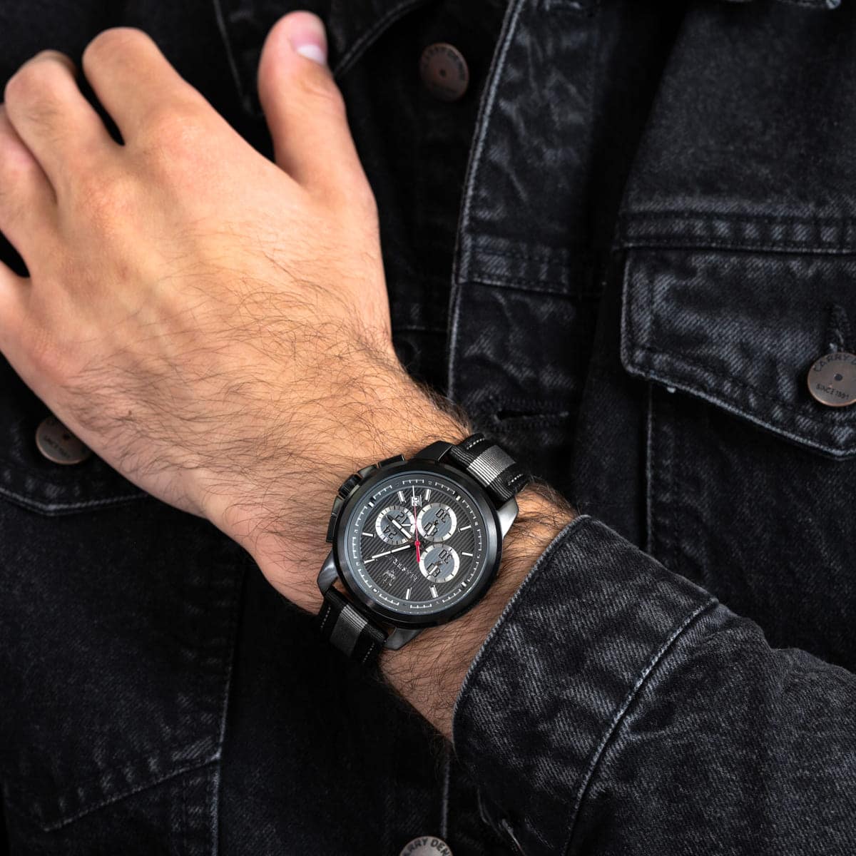 Close up of Maserati Royale R8871637002 men's quartz battery watch on wrist showing black racing dial and grey striped fiber strap
