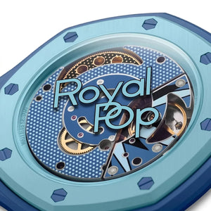 Close-up of a mechanical watch with 'Royal Pop' branding on a light blue background