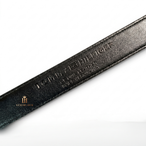 Black leather belt with 'Tommy Hilfiger' branding on a white background