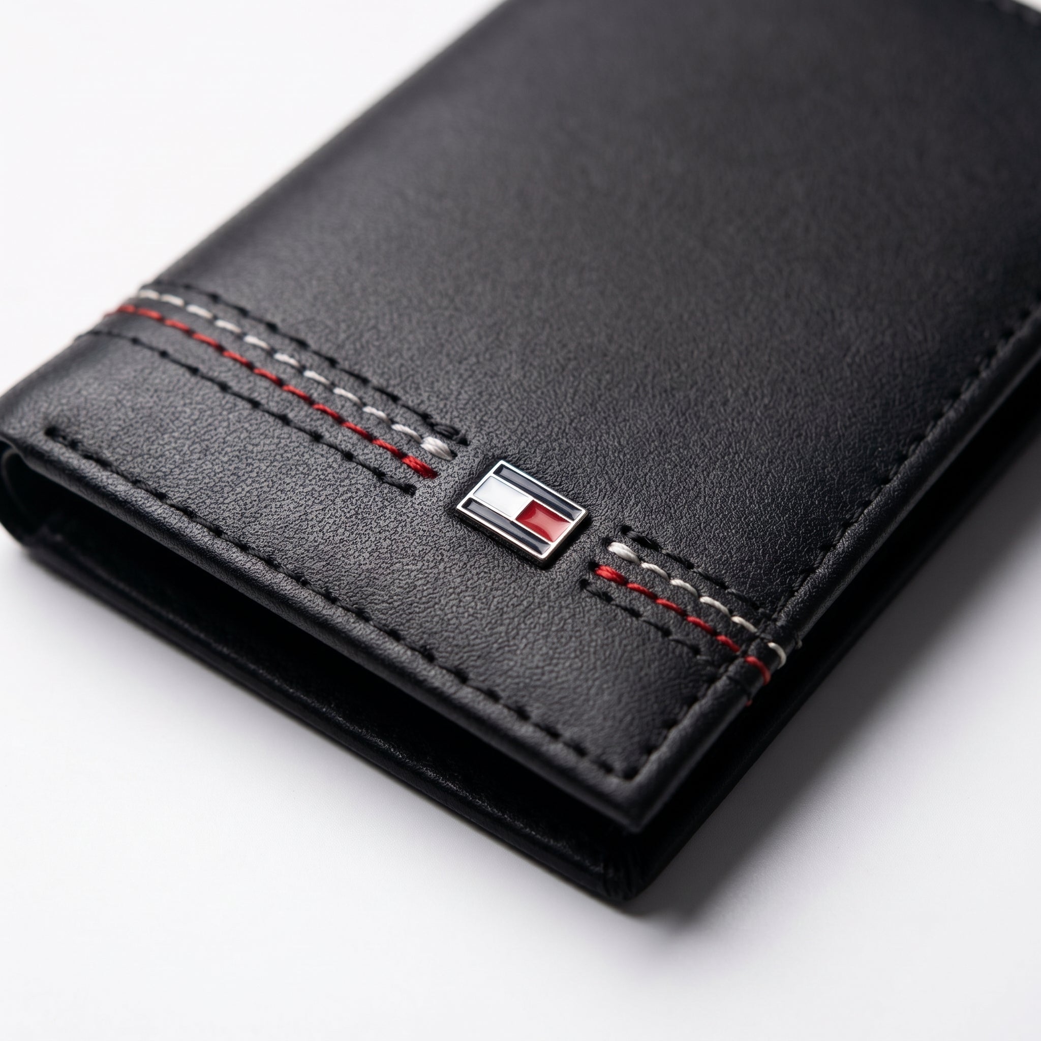 Macro close-up view showing the high-quality smooth leather texture and precision embedded Tommy Hilfiger metal enamel flag logo