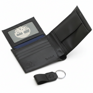 Interior view of an open Timberland black leather wallet showcasing card slots and an ID window with the tree logo, paired with a matching leather keychain