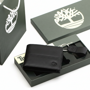 Complete Timberland men's gift set featuring a black leather bifold wallet with an embossed tree logo and a matching leather keychain, shown with premium green branded packaging