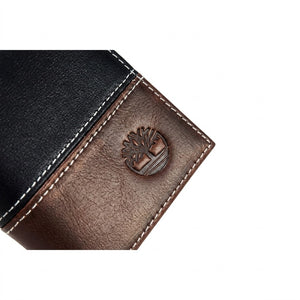 Live front view photograph of the Timberland smooth black and brown leather trifold wallet highlighting the round silver metal tree hardware logo corner accent