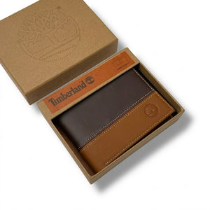Live smartphone photograph of the Timberland mirror original two-tone brown leather bifold wallet with silver tree logo resting inside the custom black box tray