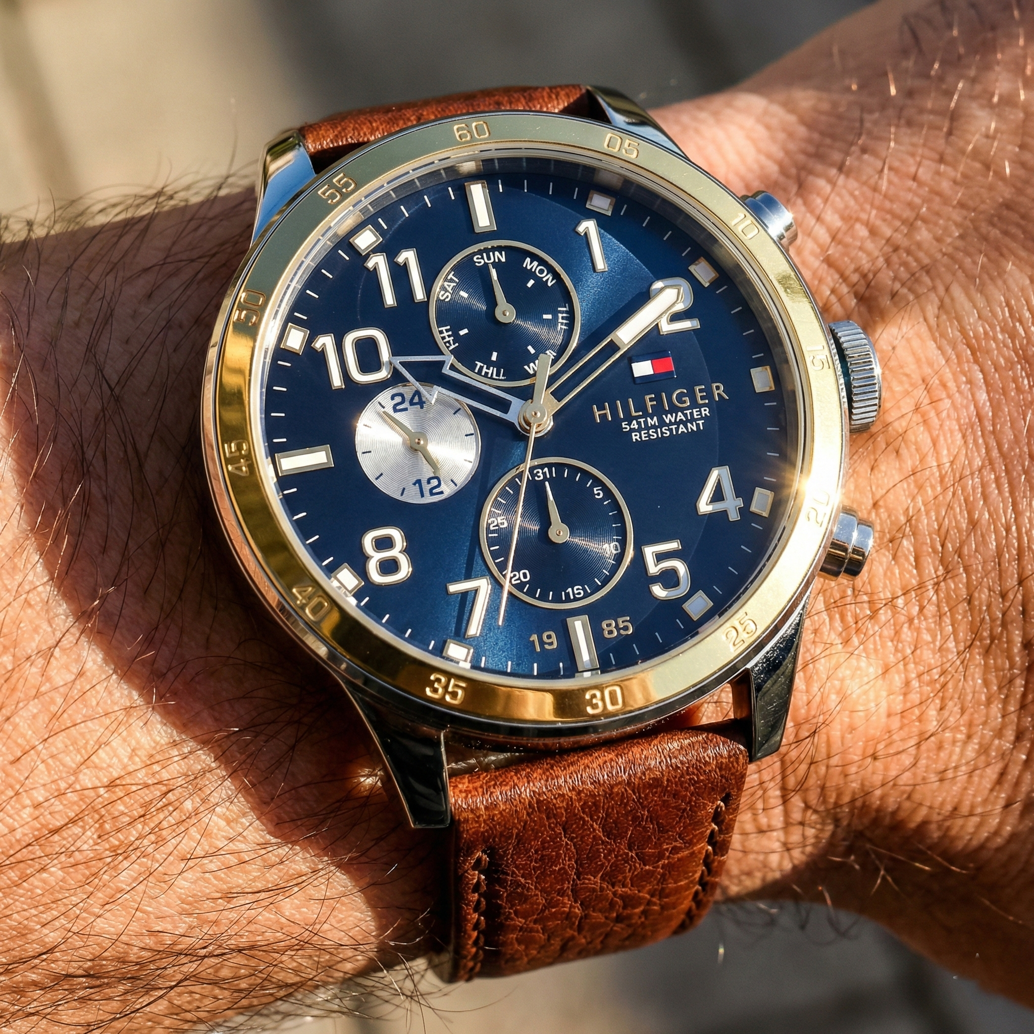Close up shot of Tommy Hilfiger 1791137 watch on wrist showing the gold bezel and blue dial