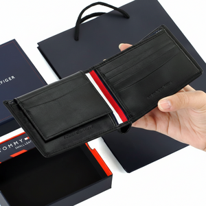 Handheld display of an open Tommy Hilfiger Black leather wallet, showcasing the internal compartments and the embossed brand name