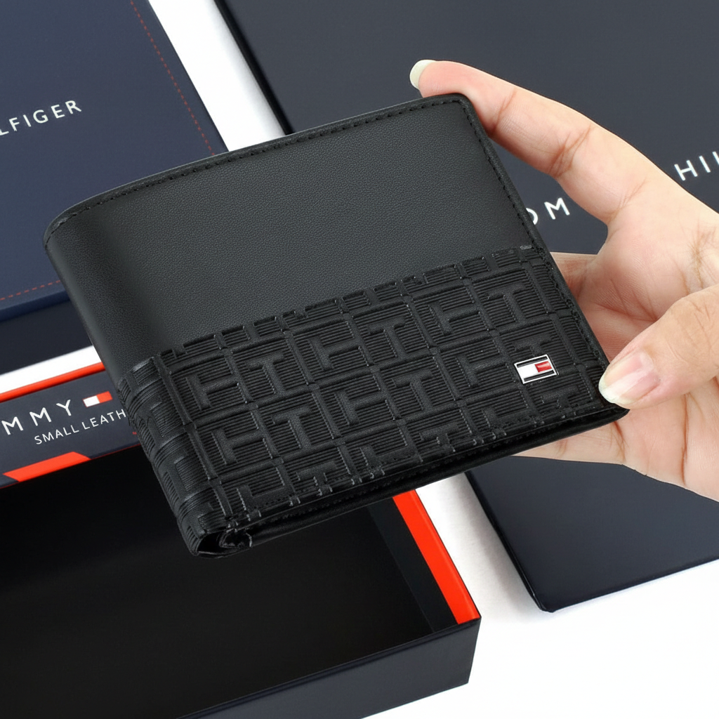 Hand holding a black textured wallet with a brand logo against a blurred background