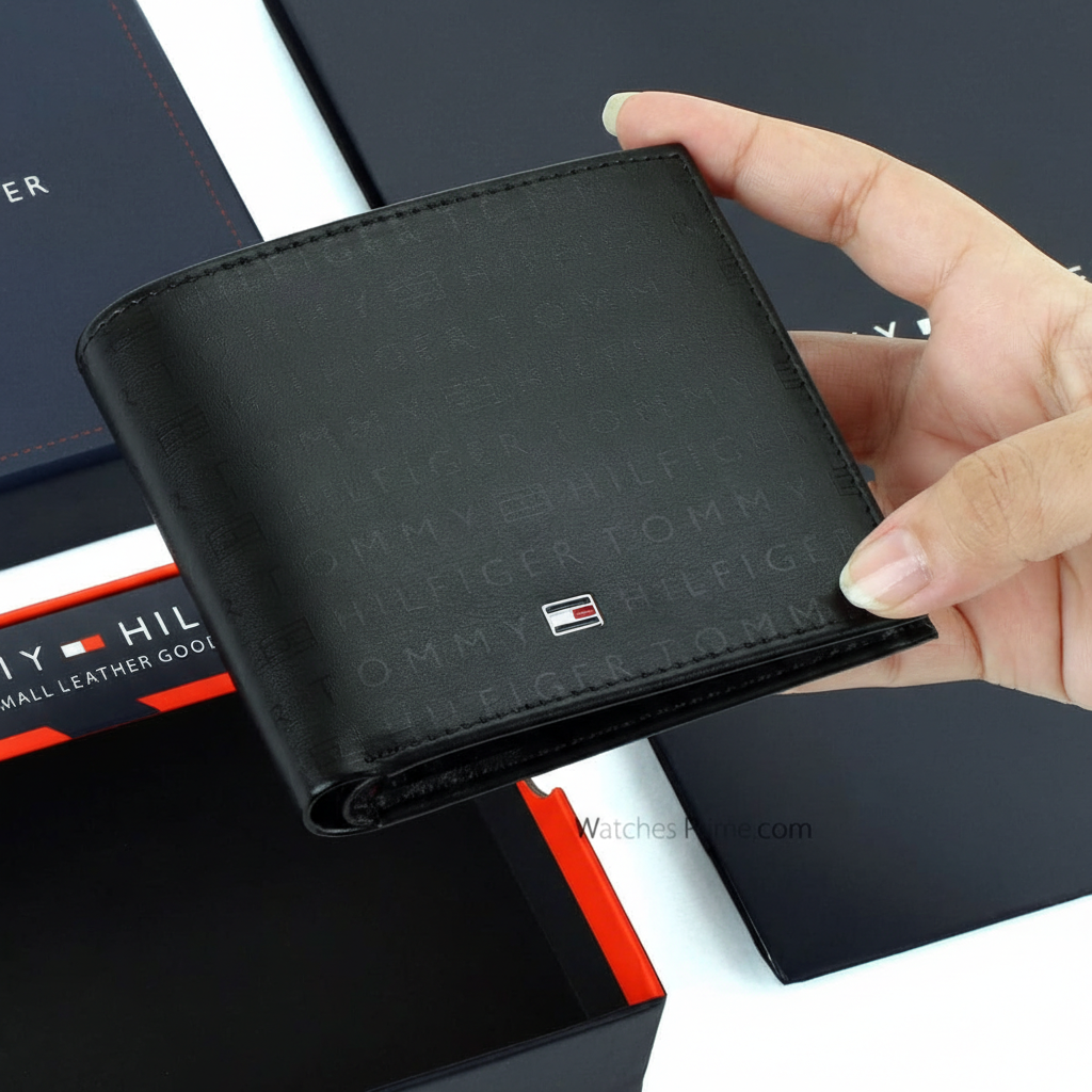 Handheld perspective of the Tommy Hilfiger black leather monogram wallet highlighting the compact bifold design and premium embossed texture