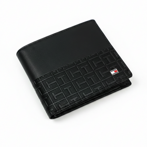 Angled view of Tommy Hilfiger black leather wallet featuring smooth top panel and geometric monogram embossed bottom with flag logo
