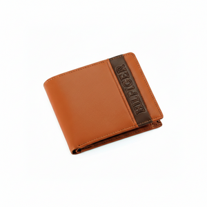 High-detail close-up of the brown vertical stripe with embossed HILFIGER branding on a camel-colored Tommy Hilfiger genuine leather wallet
