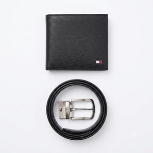 Close-up product photography of the Tommy Hilfiger reversible leather belt showcasing the polished silver rotatable buckle engraved with brand text alongside black and brown leather sides