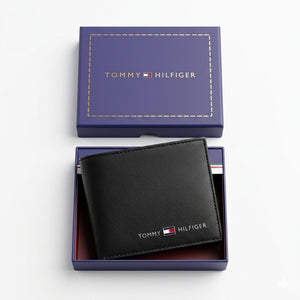 Top-down studio product photography of the Tommy Hilfiger smooth black leather wallet resting neatly inside its open premium navy branded gift box