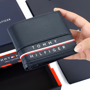 Hand holding a black Tommy Hilfiger wallet with brand logo.