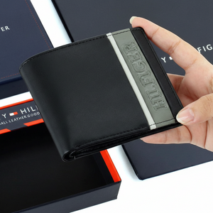 Handheld view of a Tommy Hilfiger tan genuine leather bifold wallet highlighting the high-quality smooth texture and bold embossed branding