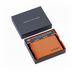 Tommy Hilfiger men's tan embossed leather wallet with monogram pattern presented inside its original navy blue branded gift box