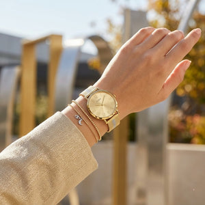 Close up of Guess U1155L3 women's quartz battery watch on wrist showing clean gold dial and gold roman numerals
