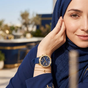 Elegant woman wearing Guess Sunrise W0616L2 women's multi-function rose gold watch with blue rubber strap, adding distinctive casual luxury style