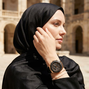 Elegant woman wearing Guess Zena W1094L6 women's quartz battery watch with rose gold case and luxury black rubber strap