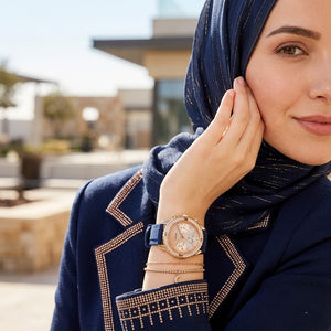 Elegant woman wearing Guess Confetti W1098L6 women's multi-function rose gold watch with blue rubber strap, adding distinctive casual luxury style