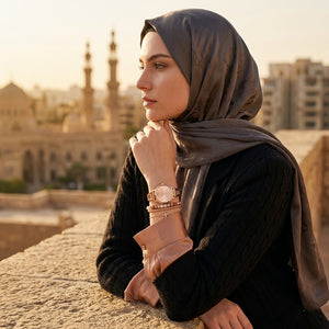 Elegant woman wearing Guess W1145L4 women's quartz battery watch with rose gold case and luxury bangle bracelet