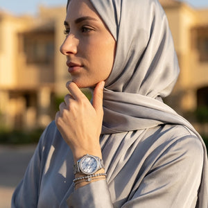 Elegant woman wearing Guess Claudia W1279L1 women's quartz battery watch with silver case and luxury printed mesh bracelet