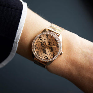 Gold watch with diamond accents on a wrist against a dark background