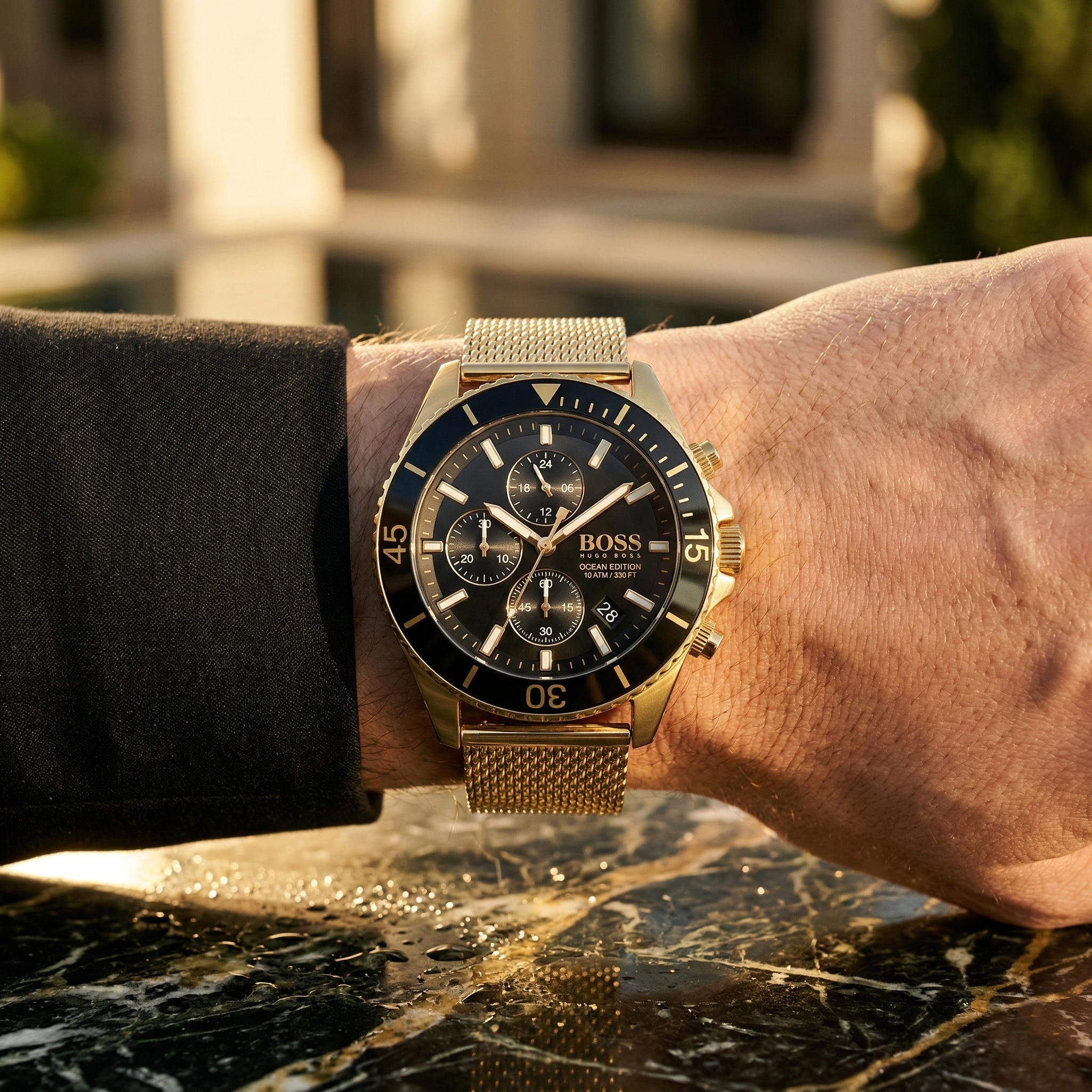 Close up of Hugo Boss Ocean Edition 1513703 on wrist showing black dial and gold metal mesh strap with 100m water resistance