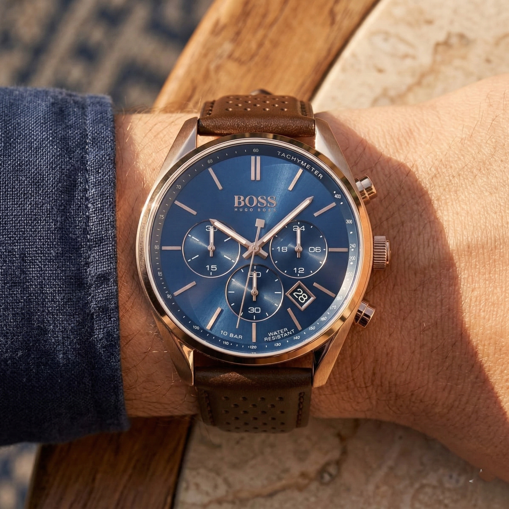 Close up of Hugo Boss Champion 1513817 on wrist showing blue dial and perforated brown leather strap with 100m water resistance