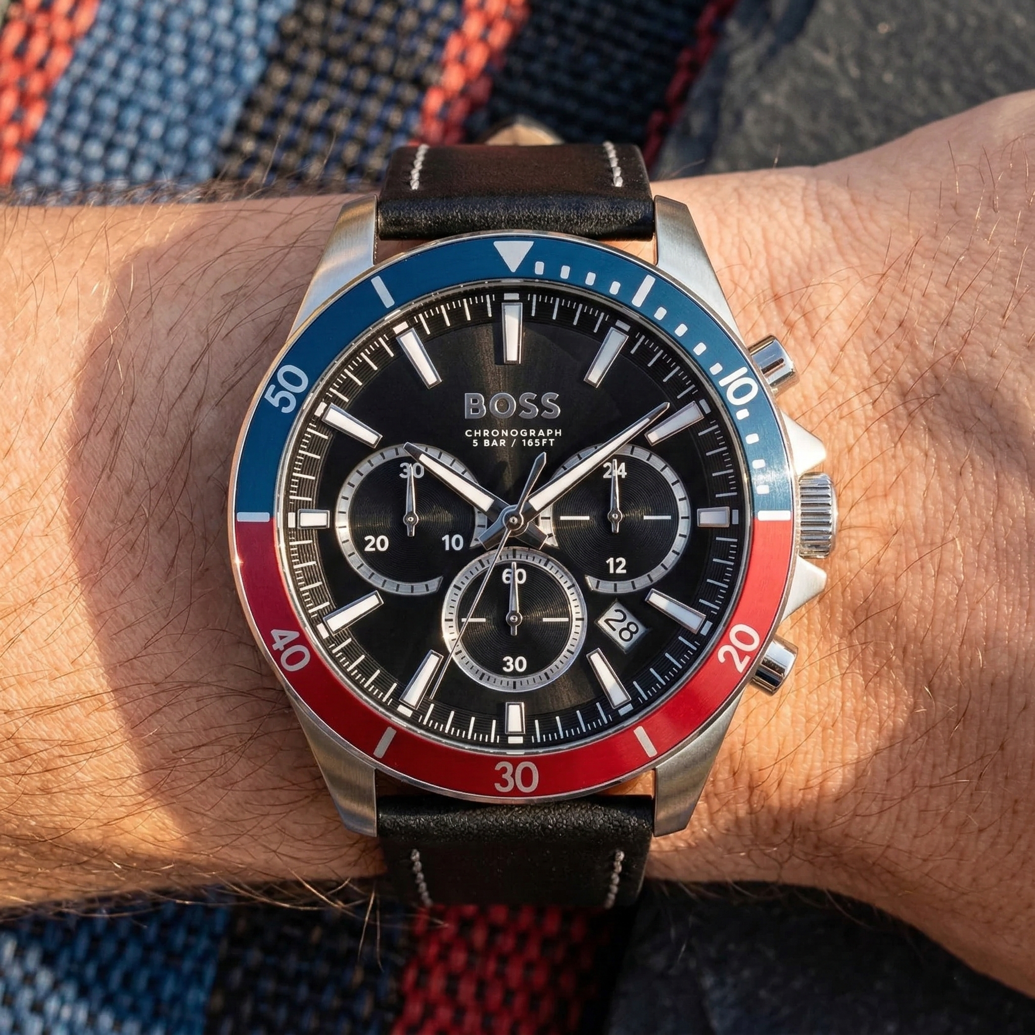Close up of Hugo Boss Troper 1514099 on wrist showing black sunray dial and blue red bezel with 50m water resistance