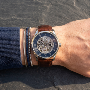 Close up of Hugo Boss Principe 1514305 men's automatic watch on wrist showing intricate navy blue skeleton dial and brown leather strap