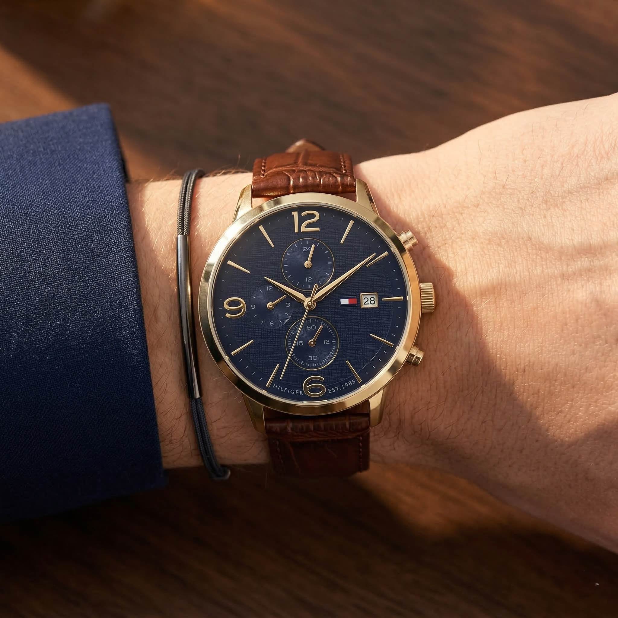 Elegant man wearing Tommy Hilfiger Liam 1710359 men's quartz battery watch with gold-tone case and luxury blue dial