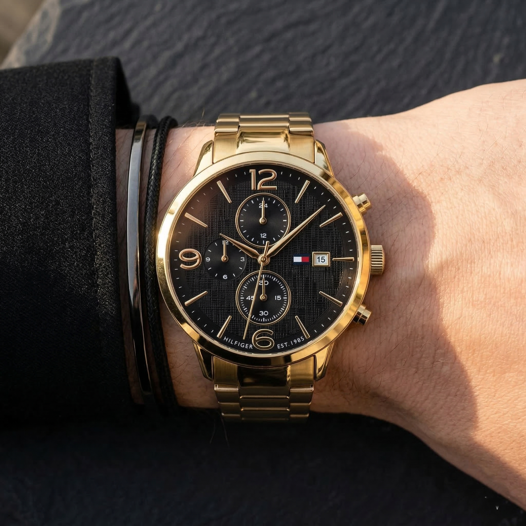 Close up of Tommy Hilfiger Liam 1710362 men's quartz battery watch on wrist showing black textured dial and gold metal bracelet