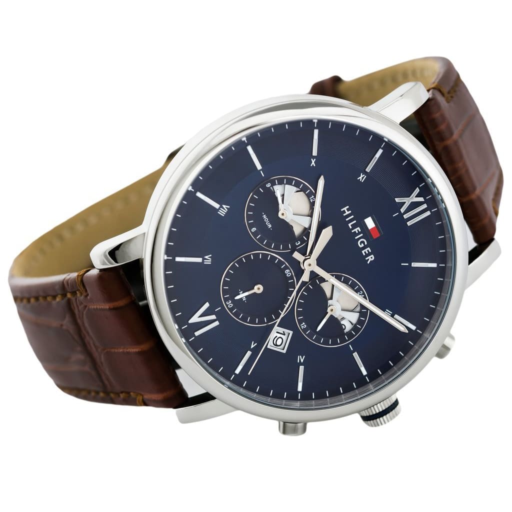 Angled profile left view of Tommy Hilfiger Evan Men's 1710393 watch highlighting dynamic flexible integrated rich brown genuine leather genuine leather strap structure dynamic contrasting white stitch details polished stainless steel buckle clasp central Analogue central minute track dynamic casually luxurious style visual casual dynamic visual casual utility