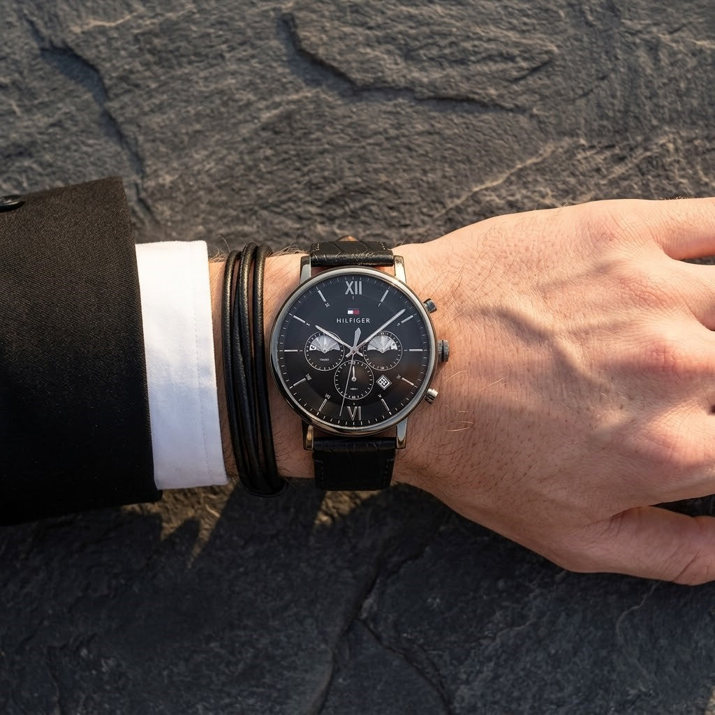 Close up of Tommy Hilfiger Evan 1710395 men's chronograph analog watch dial on wrist angled profile view showing distinct dynamic black sunray dial luminous hands applied gold stick indices gold sub-dials minutes seconds 24-hour time date window dotted central minute track visual dynamic casual luxury jewelry-like appearance dynamic visual dynamic casually luxurious visual style visual dynamic visual dynamic casual luxury visual dynamic visual casual luxury