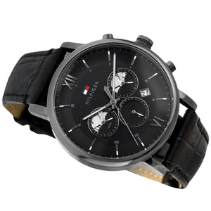 Angled profile right view of Tommy Hilfiger Evan Men's 1710395 watch showing polished round silver stainless steel case plain smooth bezel protective crown detailed integrated protected area and textured rich black genuine calfskin leather strap with white contrast stitching dynamic visually casual utility visual dynamic visual style visual dynamic visual utility dynamic casual utility